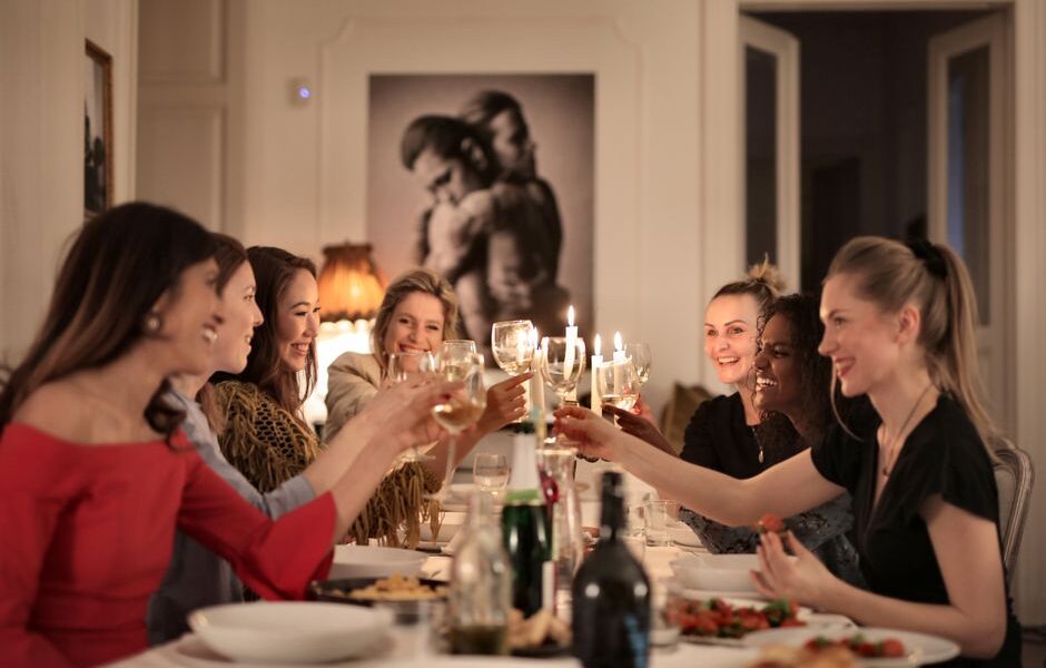 Grupa kobiet wznosząca toast kieliszkami przy suto zastawionym stole w jadalni