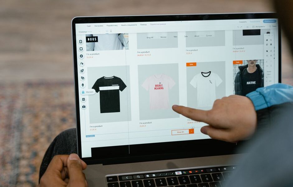 Osoba wskazująca palcem na ekranie laptopa siatkę produktów sklepu internetowego