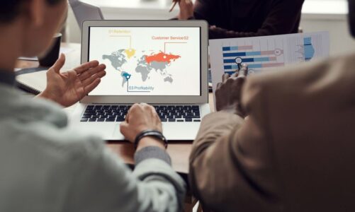 Zespół analizujący mapę świata z danymi biznesowymi na ekranie laptopa