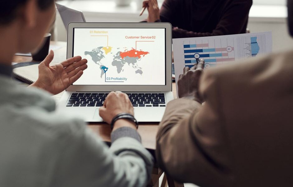 Zespół analizujący mapę świata z danymi biznesowymi na ekranie laptopa