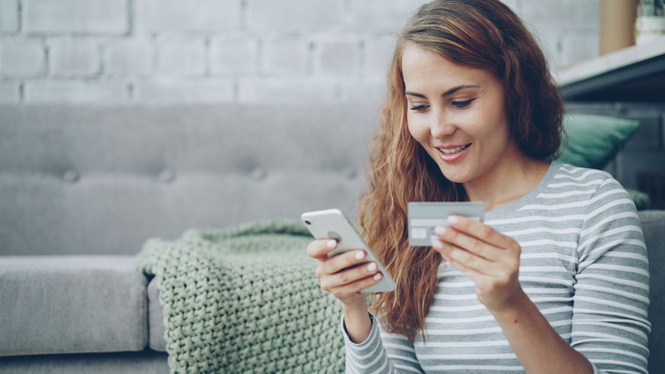 Kobieta trzymająca smartfon i kartę płatniczą podczas zakupów online