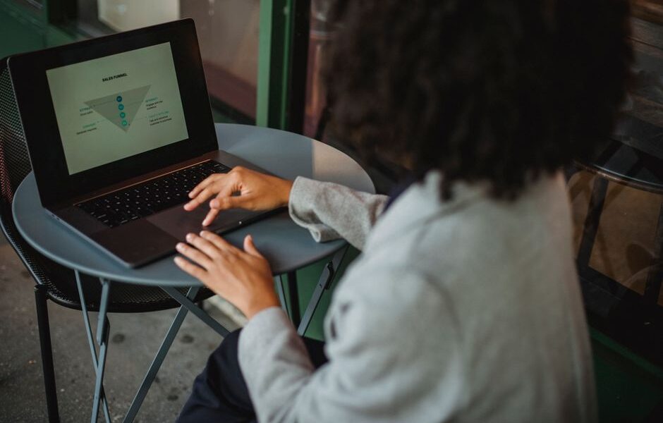 Osoba pracująca przy laptopie z wyświetlonym schematem lejka sprzedażowego.